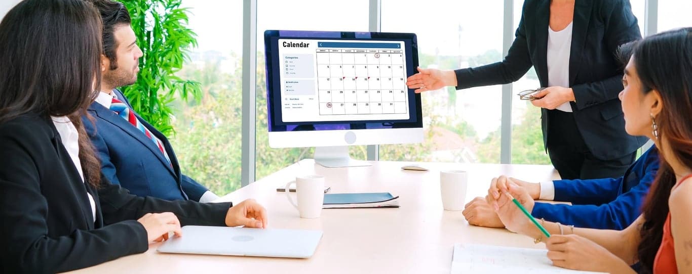 Diverse SRE team members collaborating around a screen showing an on-call schedule.
